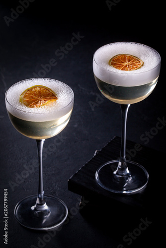 Two elegant cocktails with dried orange slices on a dark background