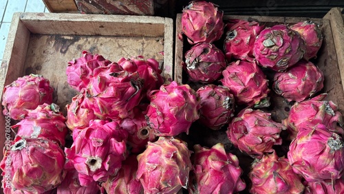 Fresh red dragon fruits or pitaya displayed in wooden crates at a local fruit market
