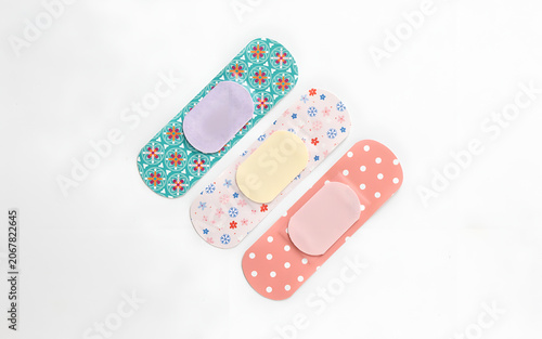 Three patterned adhesive bandages with colorful designs arranged on a plain surface