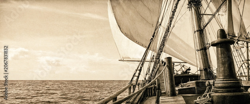 Vintage sailing ship navigating a calm ocean in sepia tones
