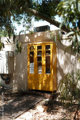 Vibrant Yellow Storage Cabinet in a Sun-Dappled Outdoor Resort Wellness Area