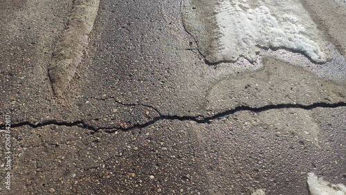 Obraz na płótnie Fissured Asphalt Pavement showing a long crack across the gray road surface