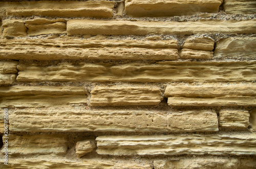 Crumbling old stone wall from yellow sandstone closeup