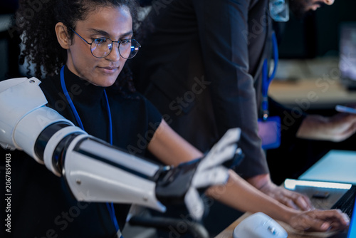 Fotografie Close-up of bionic prosthetic hands in a darkroom lit by blue AI displays during a technology demonstration event at night