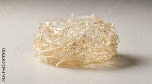 Close up of gelatinous substance with fibrous texture on a plain background.