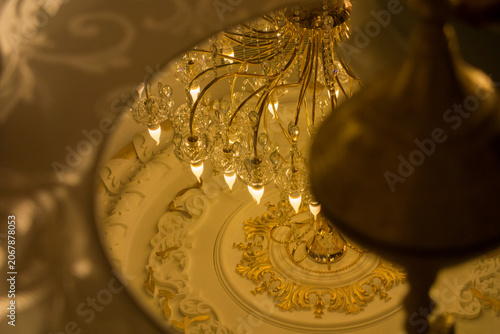Valokuva Elegant crystal chandelier with golden accents reflected in a mirror frame