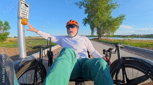 Senior cyclist is riding a full suspension recumbent tricycle on a bike trail in northern Colorado and crossing a highway - Kyger Open Space