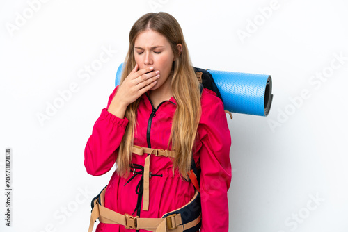 Young mountaineer girl with a big backpack over isolated white background yawning and covering wide open mouth with hand
