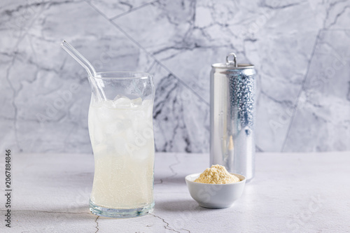 Foto Carbonated protein drink in a glass and protein powder in a bowl on a table