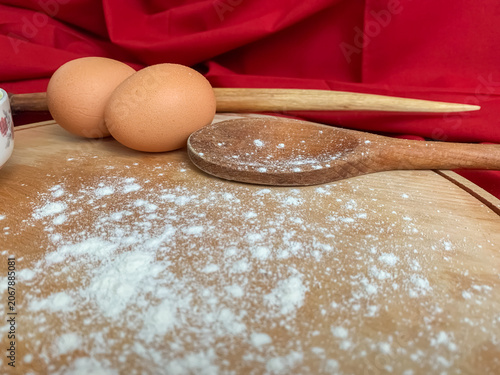 Foto Rustic kitchen scene with fresh eggs and a wooden spoon on a floured board