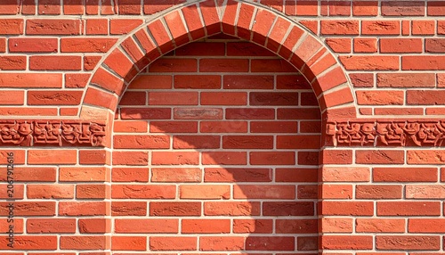 Red brick wall with arched recess and carvings