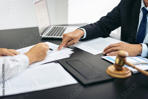 Two men are sitting at a table with papers and a gavel