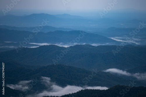 Blue hour view of the Blue Ridge Mountains, with soft twilight tones filling the sky and layers of clouds flowing between the mountain ridges, creating a calm and atmospheric landscape