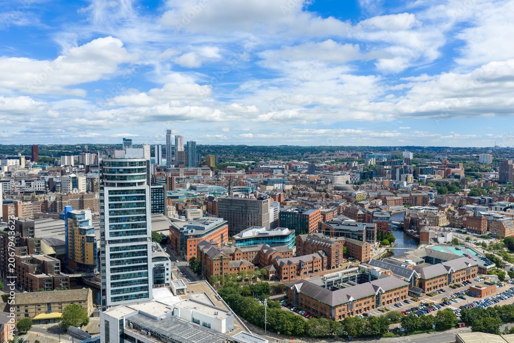 Fototapeta premium Panoramic aerial view of Leeds city centre featuring Bridgewater Place Leeds Dock modern office buildings historic warehouses and the city skyline beneath a bright summer sky with scattered clouds