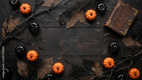 Halloween background with pumpkins, vintage book, and autumn leaves on a dark wooden table