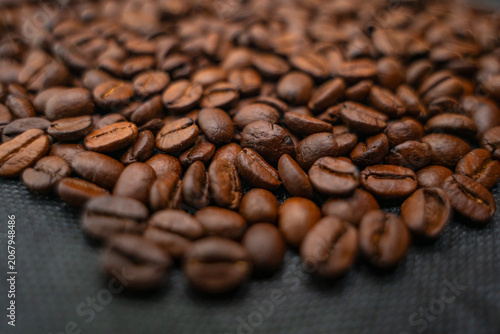 Close-up shot of roasted coffee beans piled on a dark surface.