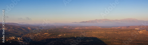 Panoramic morning view of Gouves village in Crete, Greece, taken from Mount Edheri with layer of low fog and misty horizon during sunrise
