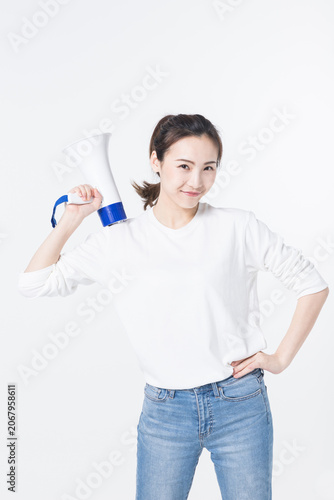 Konstfotografi Smiling young woman holding megaphone on white background