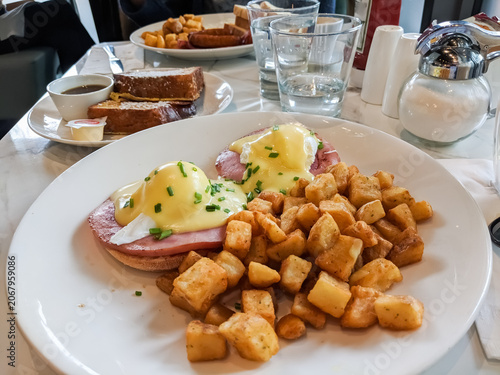 Delicious eggs Benedict with crispy hash browns served at a cozy breakfast table.