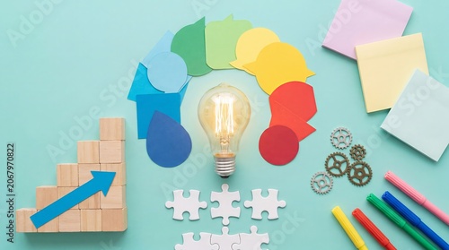 Creative business illustration showing a glowing light bulb surrounded by colorful human profile shapes. Represents diversity, inclusion, innovation, collaboration, and idea generation.
