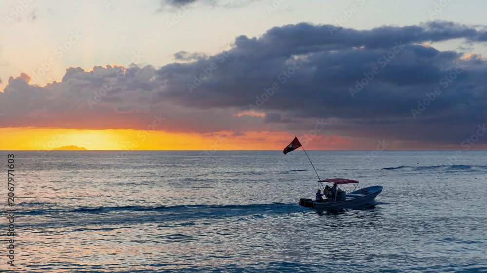 Fototapeta premium Small motorboat sailing during a golden sunset in Crash Boat Beach, Aguadilla, Puerto Rico