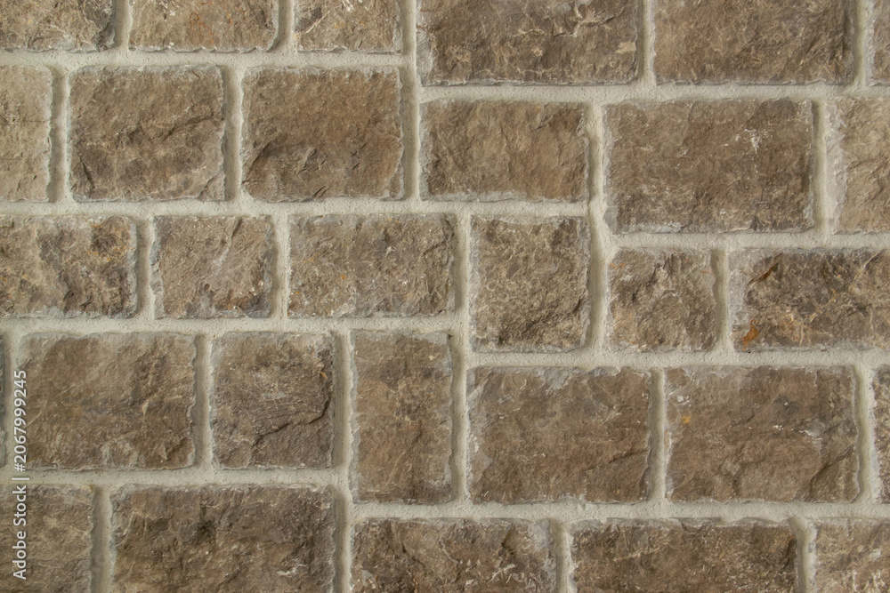 Fototapeta premium Brown stone wall texture background closeup. Decorative stone tiles background with light seams