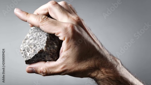 Hand showing rock on gesture, A hand grips a rock, emphasizing its rough surface and weight