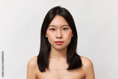 Slika na platnu Confident Young Asian Woman With Long Hair Looking Towards Camera, Showing Natural Beauty And Self-assurance In Studio Setting
