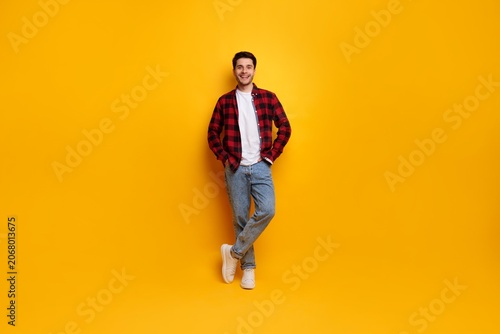 Canvastavla Smiling Young Caucasian Man Posing With Hands In Pockets, Standing At Studio With Bright Yellow Background, Displaying Casual Style And Confident Posture