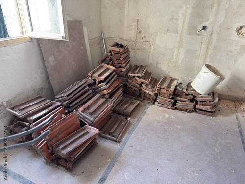 Pile of old terracotta roof tiles stacked indoors