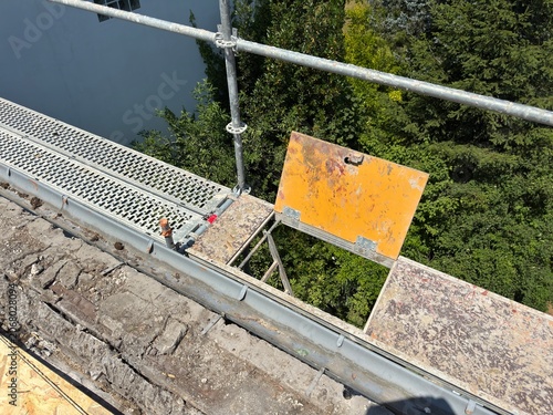 Construction scaffolding on a damaged roof with trees in background
