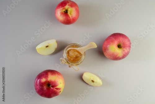 Homemade apple jam in jar with apples and spoon on light background
