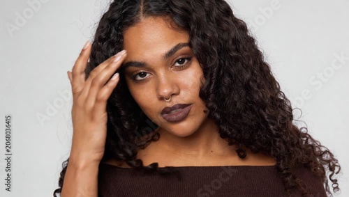 Real Black woman with natural curls and bold dark lipstick poses in brown top