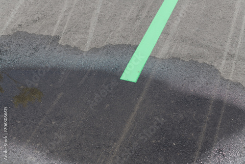 asphalt with puddle stain and green lane marker