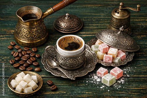 Elegant table setting with traditional coffee pot, cup of rich black coffee, sugar cubes, and colorful pastries for a delightful tea time or dessert course.