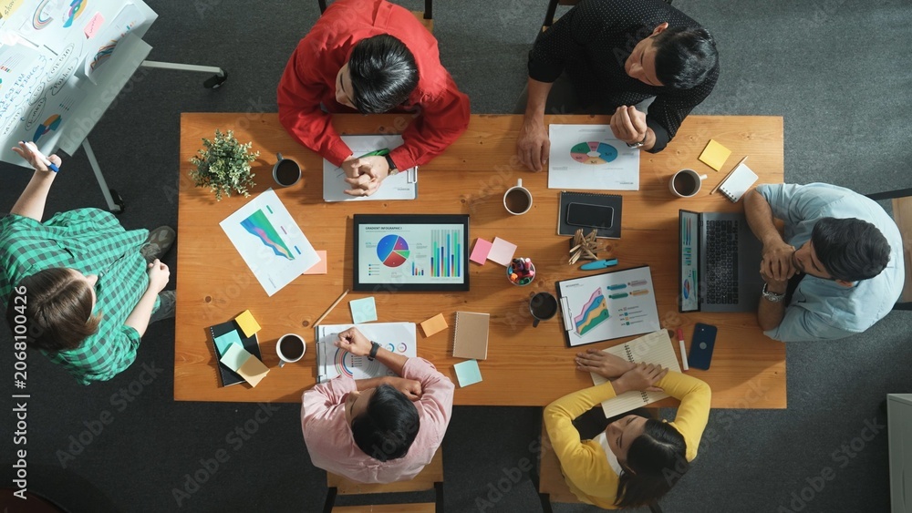 Fototapeta premium Top view of investor looking executive manager standing and presenting plan. Attractive businesswoman standing whiteboard and holding tablet display financial graph at business meeting. Convocation.
