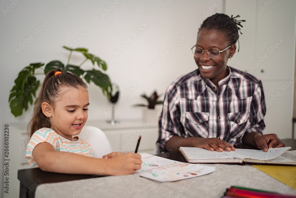 Naklejka premium Cheerful tutoring moment between child and mentor in cozy home setting