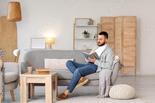 Handsome young man reading ...