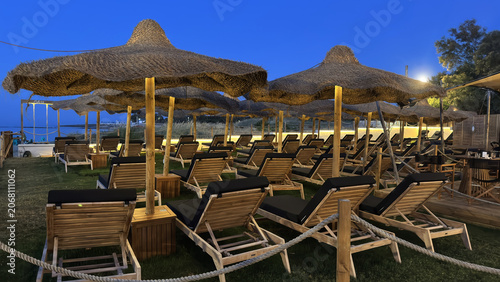 Luxury Beach Sun Loungers Under Thatched Parasols at Blue Hour by the Sea