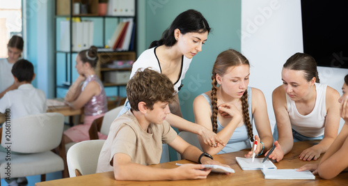 Tableau sur toile Teenagers sit at table and discuss logical task, preparation or improvisation