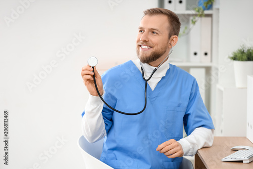 Male doctor with stethoscope at desk in clinic