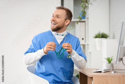 Male doctor with stethoscope at desk in clinic