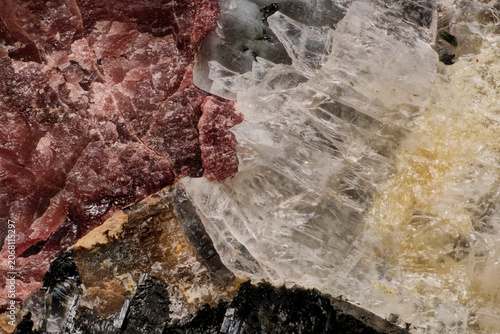 Macro image of rare minerals captured with 5X microscope objective lens: pink eudialyte, dark loparite and yellow titanite crystals in Khibiny rock