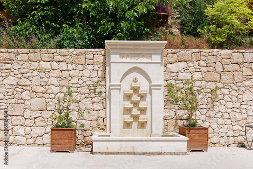 Traditional wall fountain with Arabic calligraphy and stone masonry wall inside the Khan's Palace territory