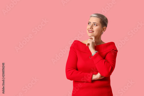 Thoughtful mature blonde woman with short hair on pink background