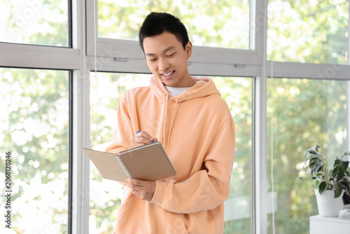 Young Asian man writing som...