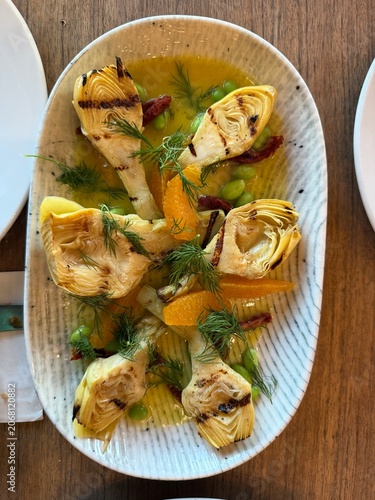 Grilled artichoke hearts with orange slices, dill and olive oil sauce.