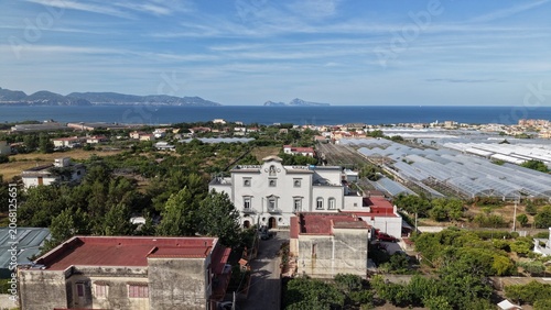 Εκτύπωση καμβά Aerial drone view of white historic villa among rooftops with coastal greenhouse