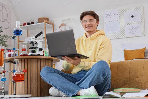 Male student in safety goggles studying with laptop at home