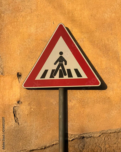 Pedestrian Crossing Warning Road Sign Against Warm Ochre Wall